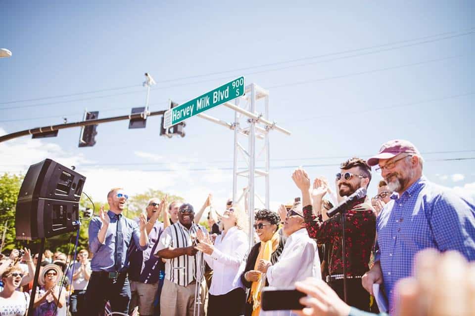 Clapping happy people under a street sign: Harvey Milk Blvd