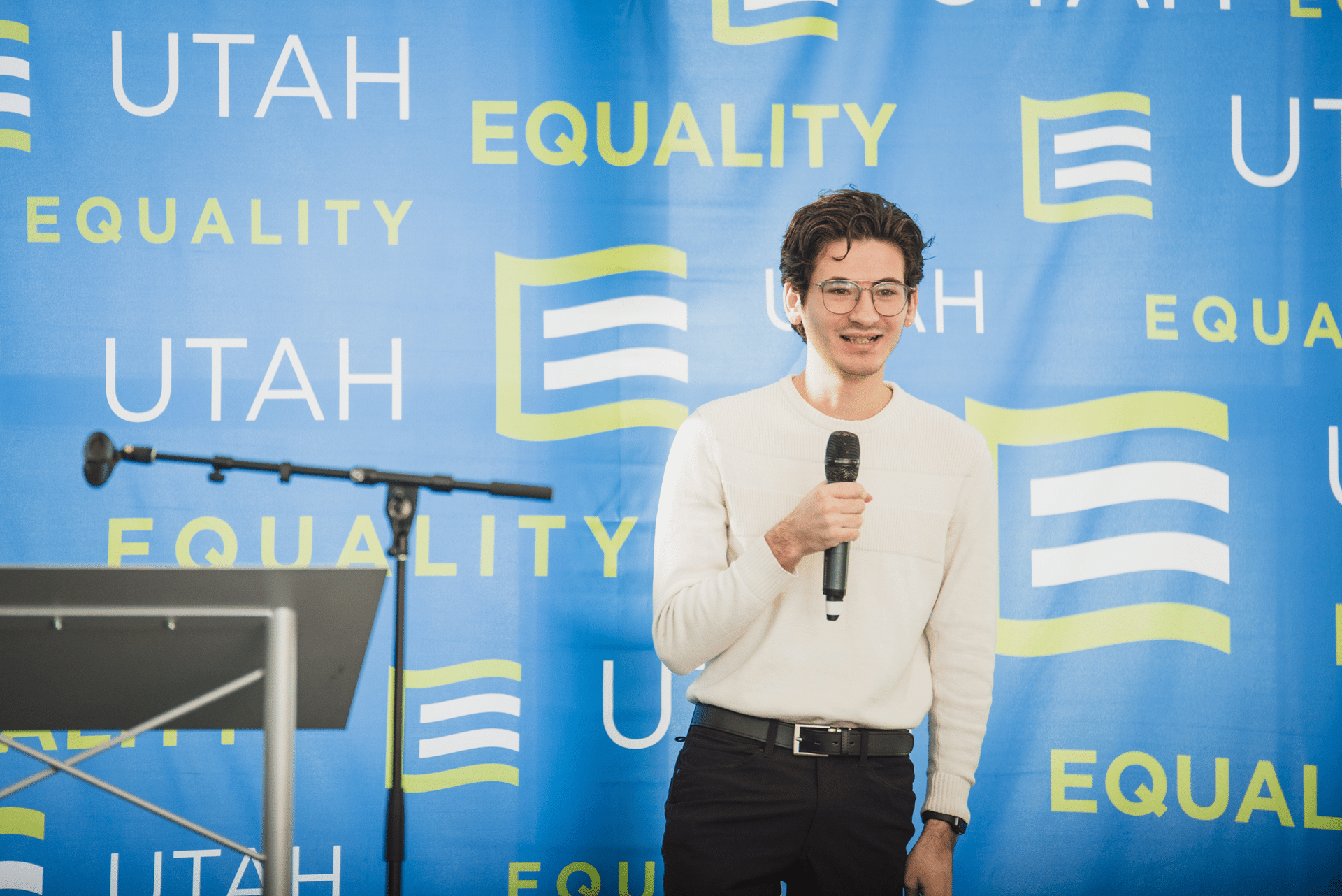 Young person speaking into microphone, Equality Utah logo behind him