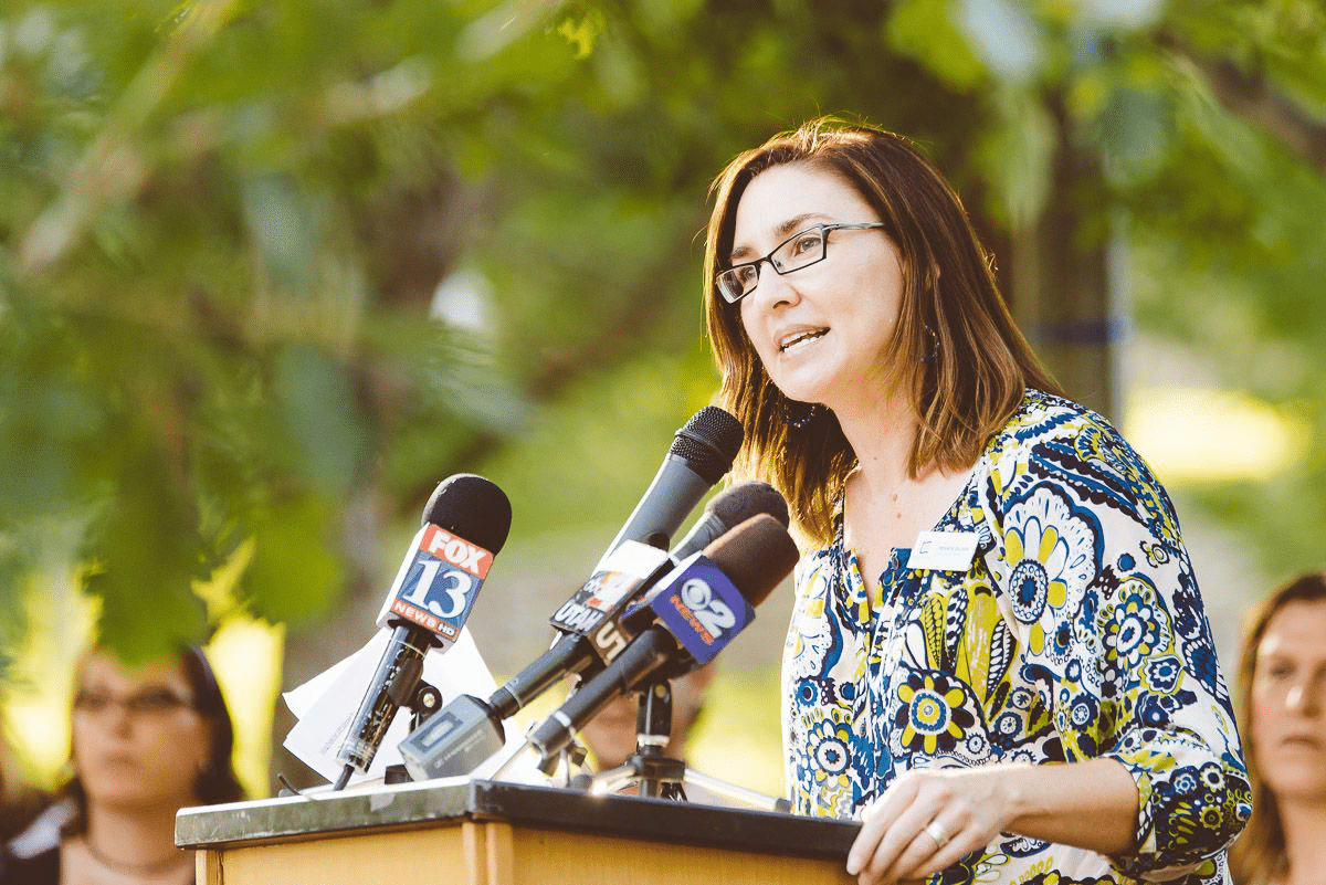 Woman speaking into microphones at podium