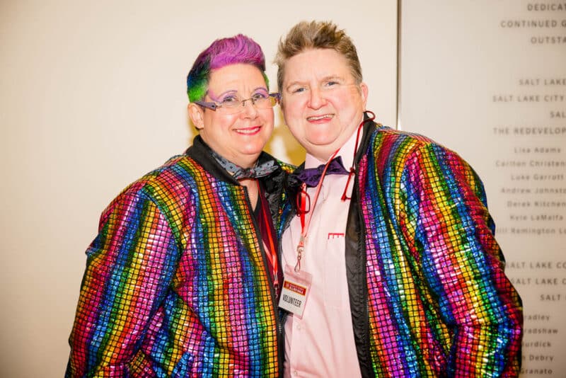 Two smiling people in colorful clothes and hair