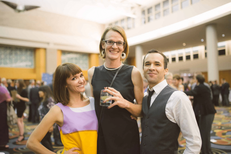 Three smiling people standing in formal attire