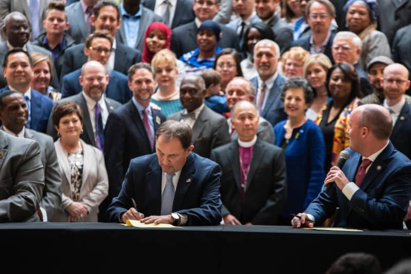 A large crowd watches a man sign a bill