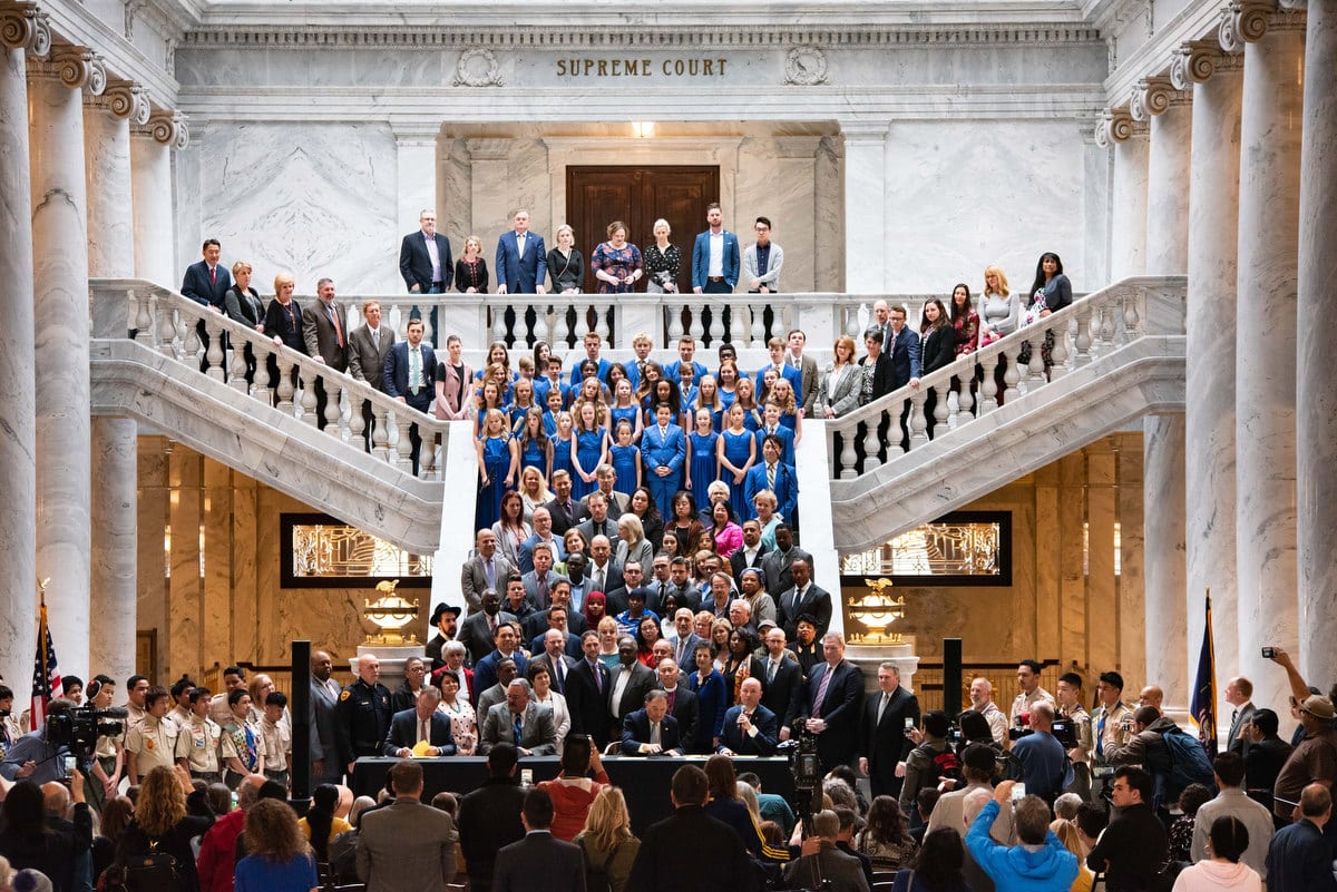 A large crowd inside of the Utah Capitol onlooking a panel of men signing a bill