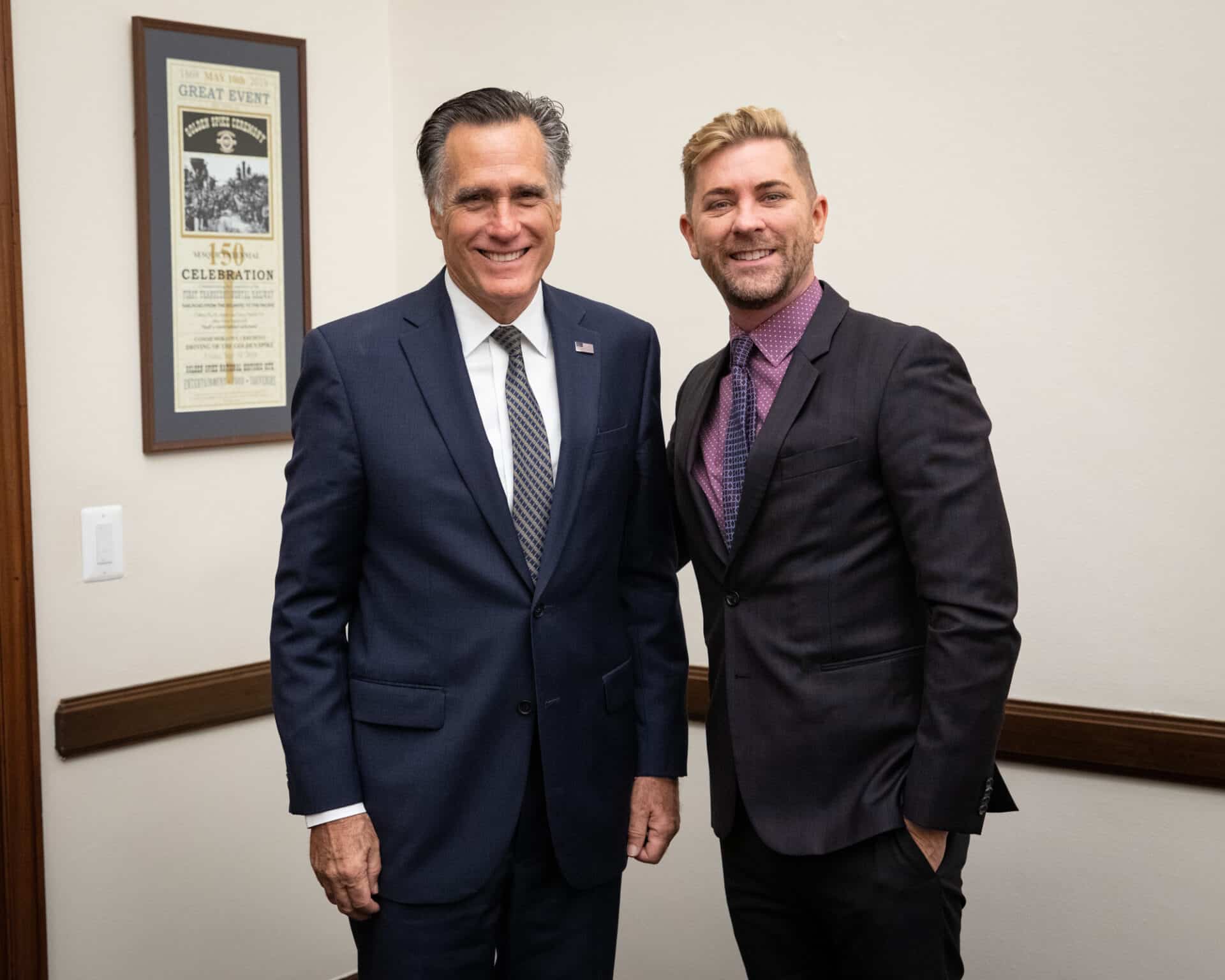 Mitt Romney and Troye Williams pose together indoors.